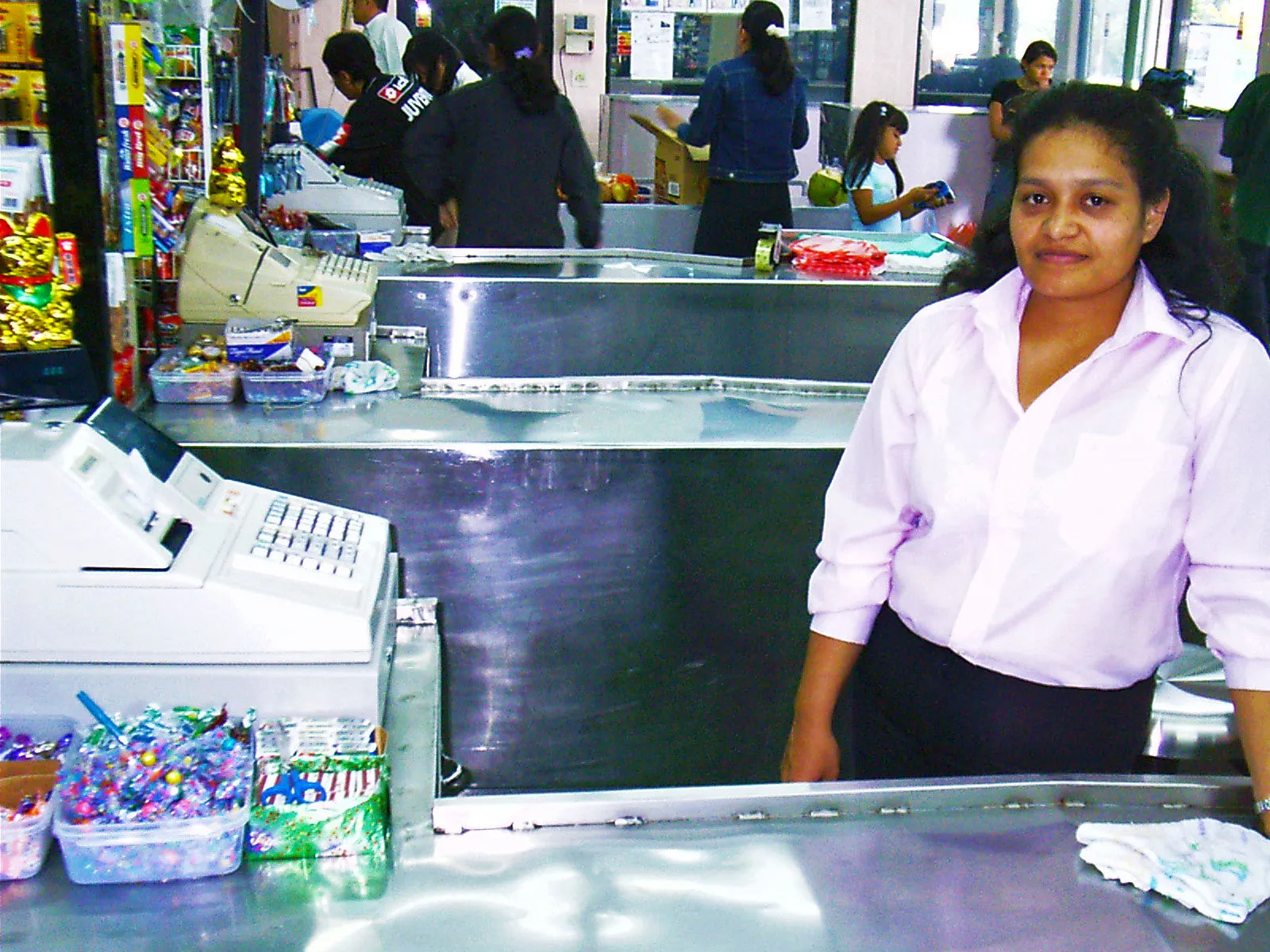 Kasir toko dengan mesin kas tradisional di depan pelanggan